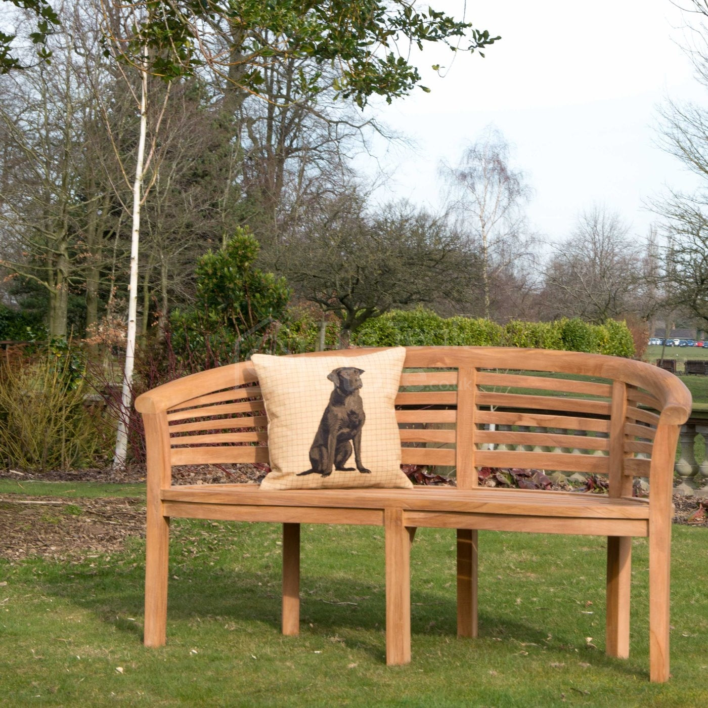 Lewes curved teak bench placed in a landscaped garden setting.