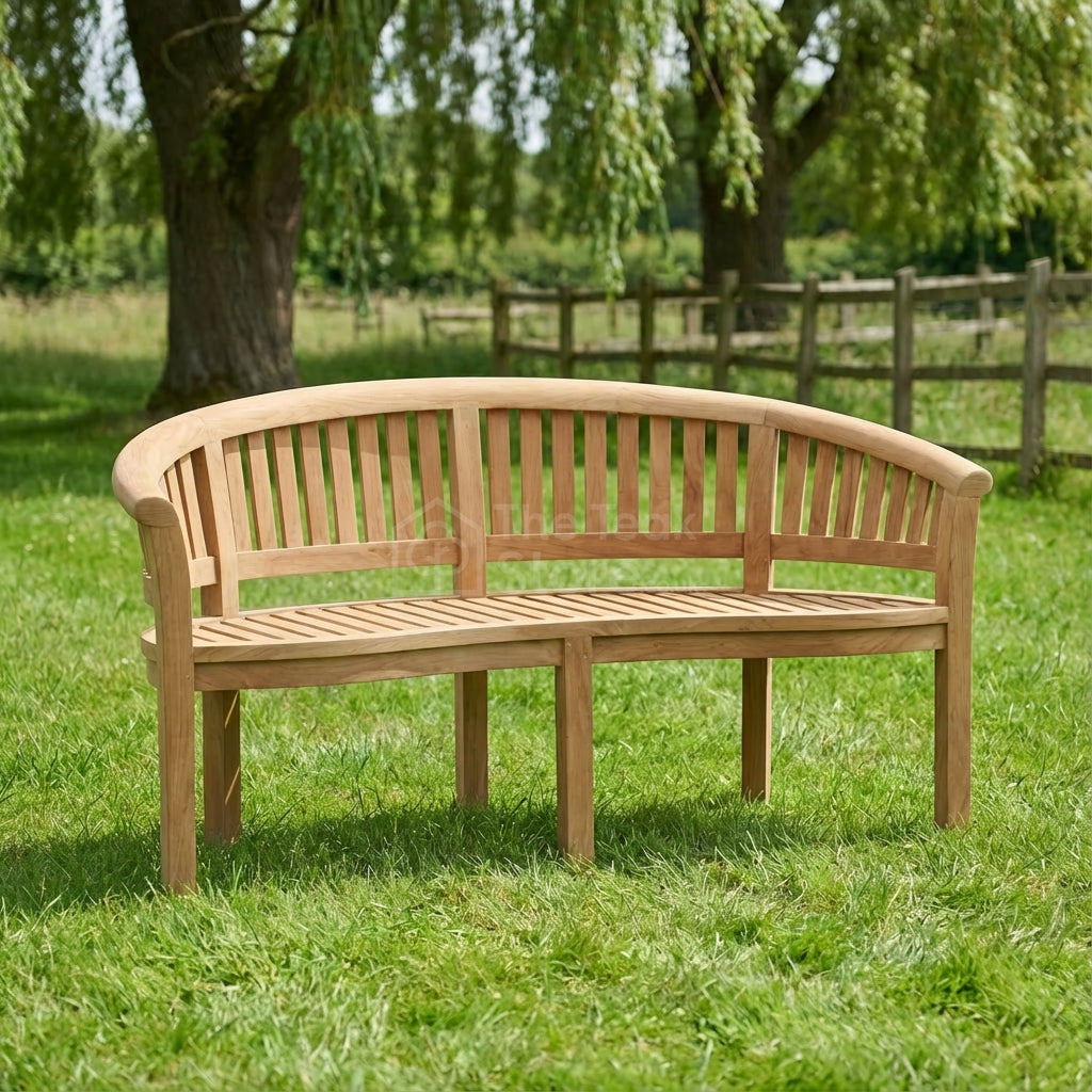 Wooden bench with a blanket and camera on grass with trees and fence in the background